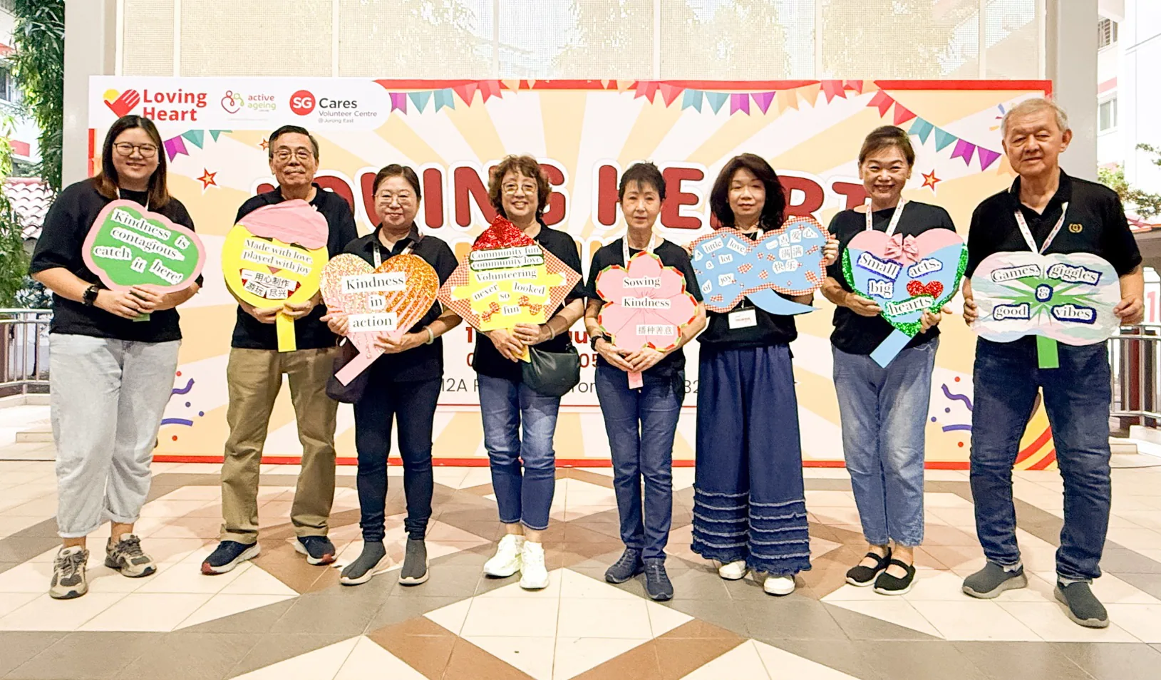 SKS volunteers holding kindness signs in front of the Loving Heart banner