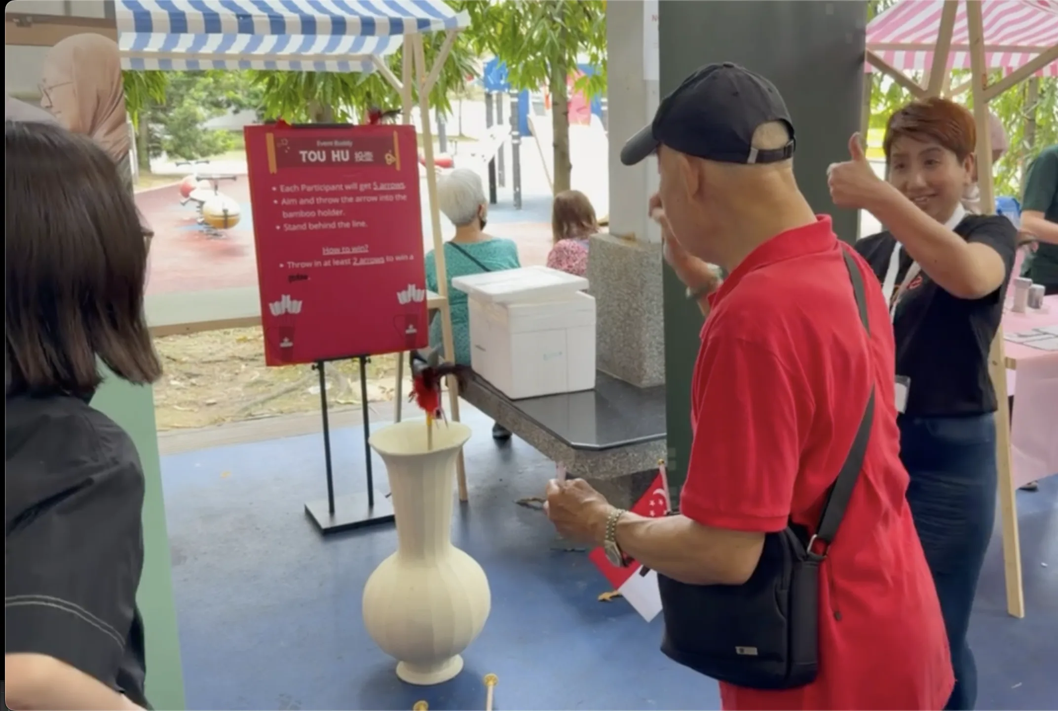 Volunteer at the Tou Hu booth helping a participant aim
